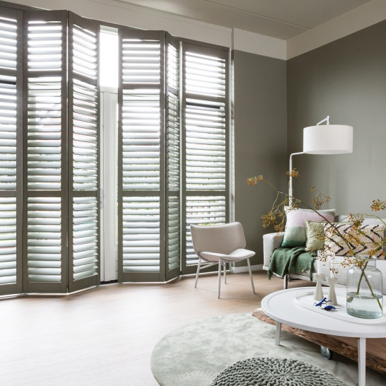 Sfeerfoto van woonkamer met houten shutters in kleur 7003 Moss Grey, op rails